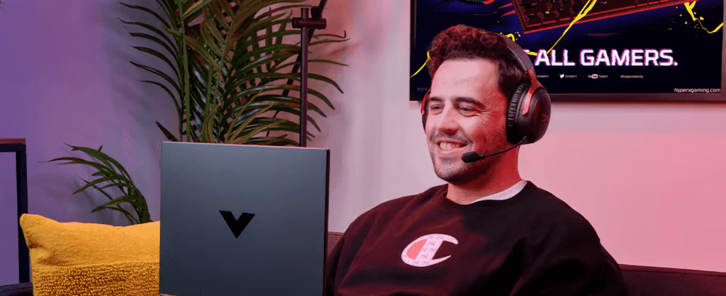 Hombre utilizando laptop HP Victus con auriculares Hyperx