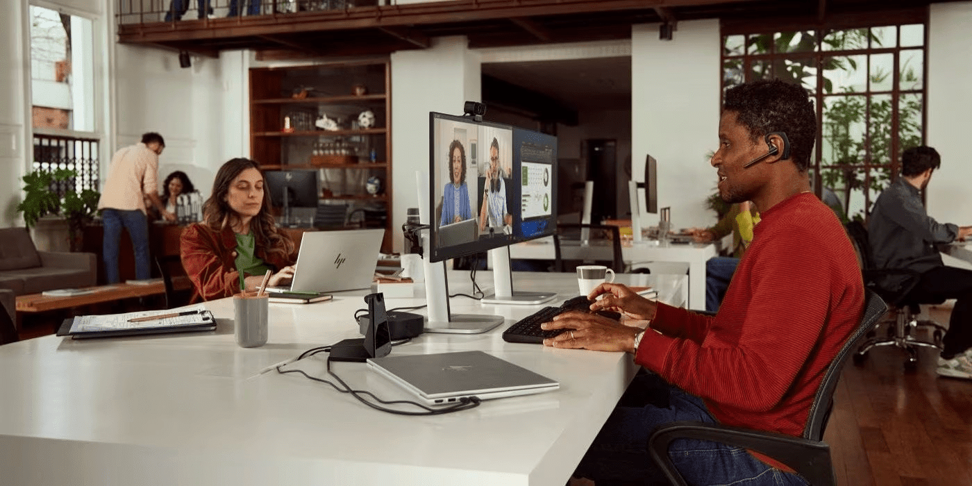 Persona trabajando en un ecosistema HP: Workstation mobil + Monitores duales HP.